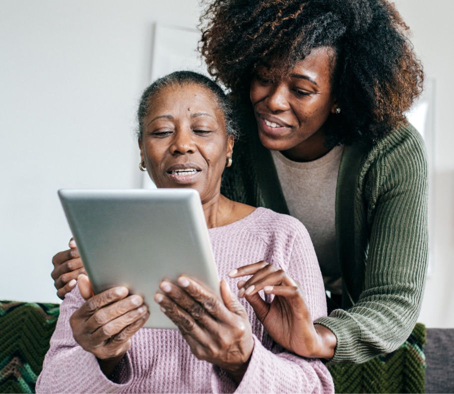 memory-care-patient Woman helps senior navigating tablet.