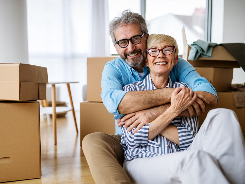 Couple embracing surrounded by moving boxes. 