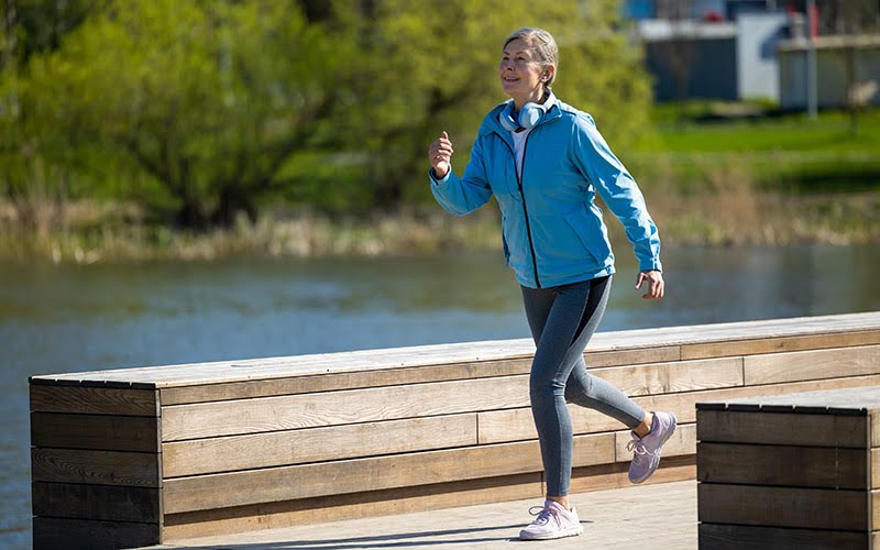 Mature woman jogging in the park and looking concentrated using an apple watch
