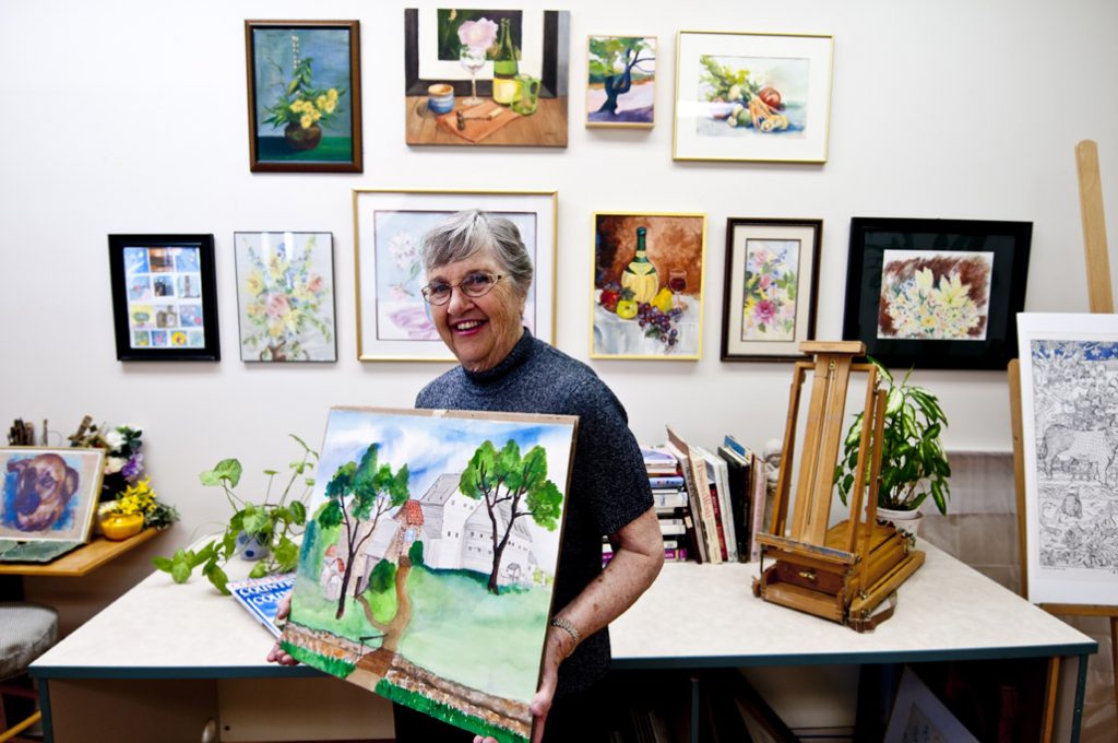 Ginger Cove resident holding her painting of a home