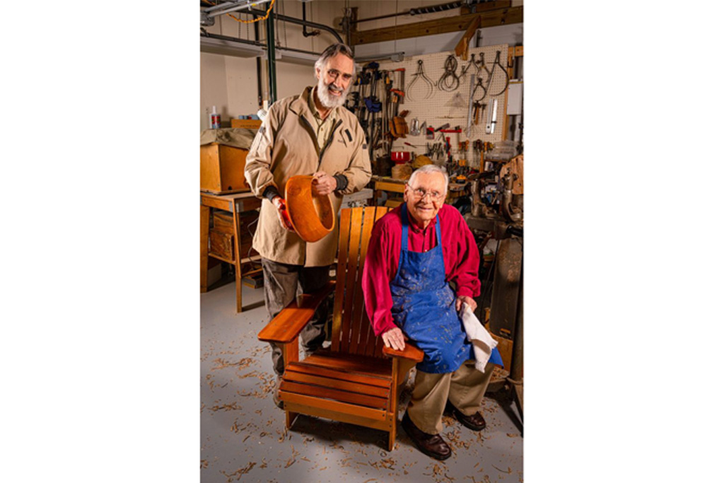 Ginger Cove residents in woodshop showing; left resident is holding a handmade wooden bowl, and right resident is sitting on handmade chair.