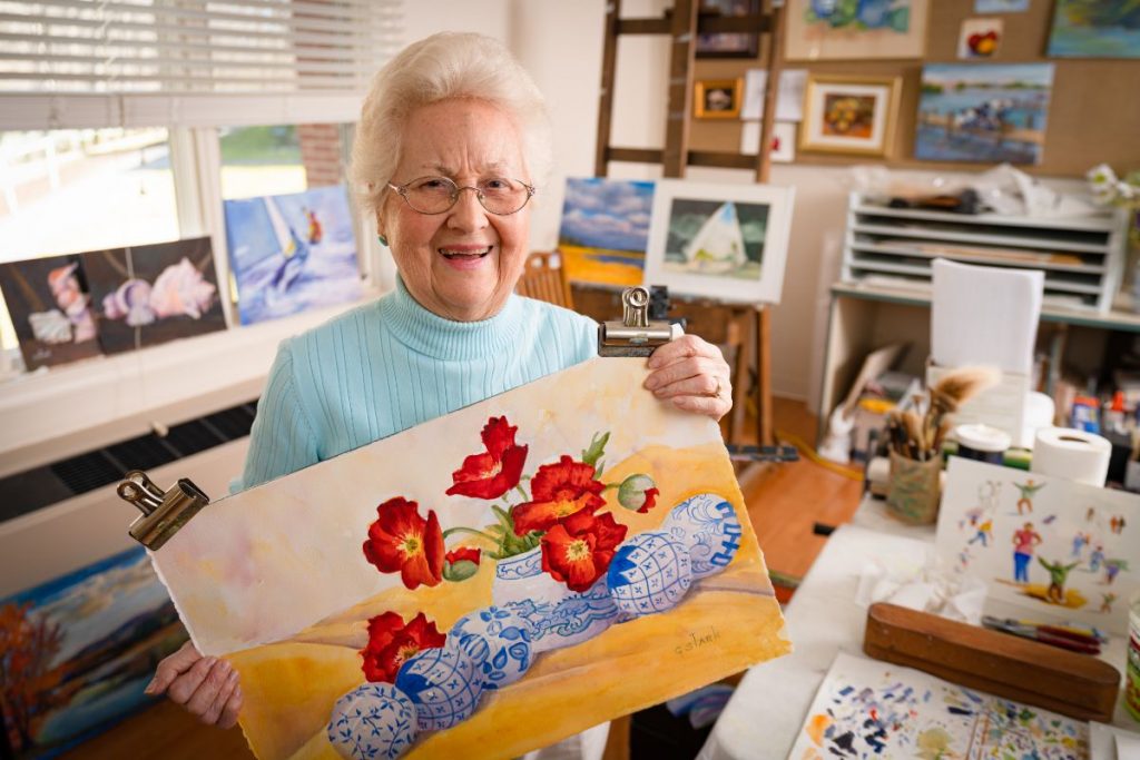 Ginger Cove resident holding her painting of flowers