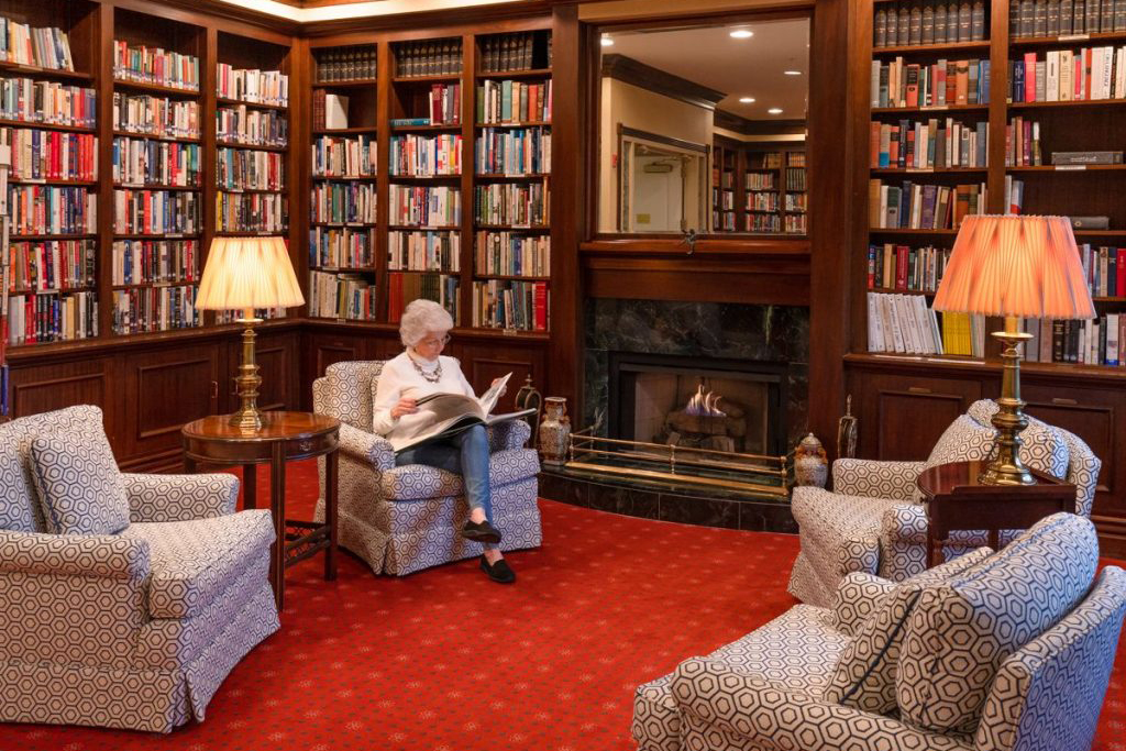 Ginger Cove resident reading book in library armchair