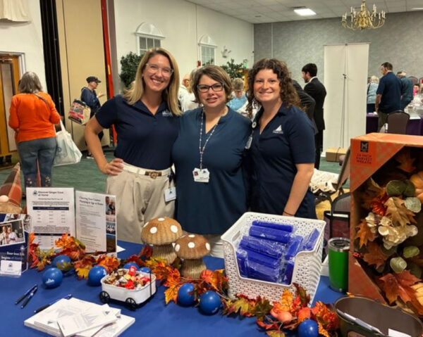 Ginger Cove employees smiling behind table display at exhibit