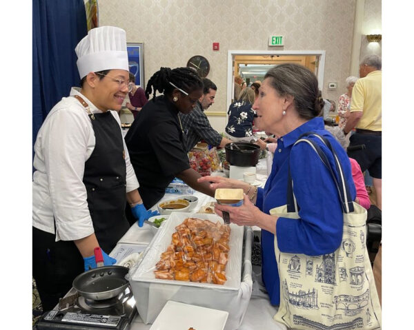 Ginger Cove chef smiling at resident above food display
